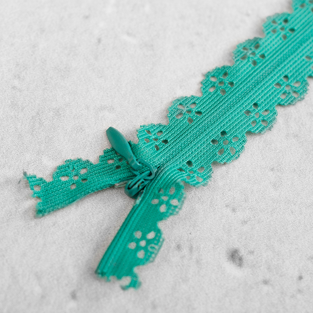 Zamek kryty z delikatną taśmą koronkową, wyposażony w subtelny&nbsp;suwak.