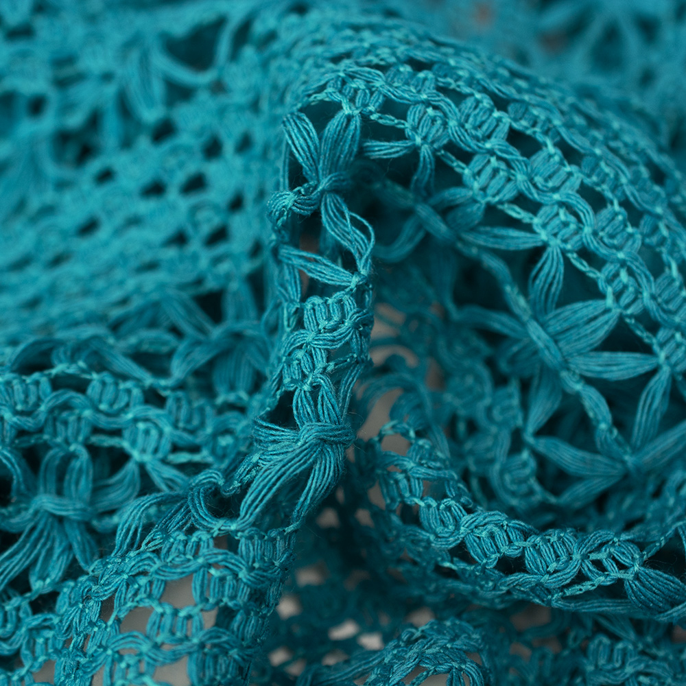 Ażurowa koronka pleciona z grubej, skręconej przędzy o jednolitym, kremowym zabawieniu.