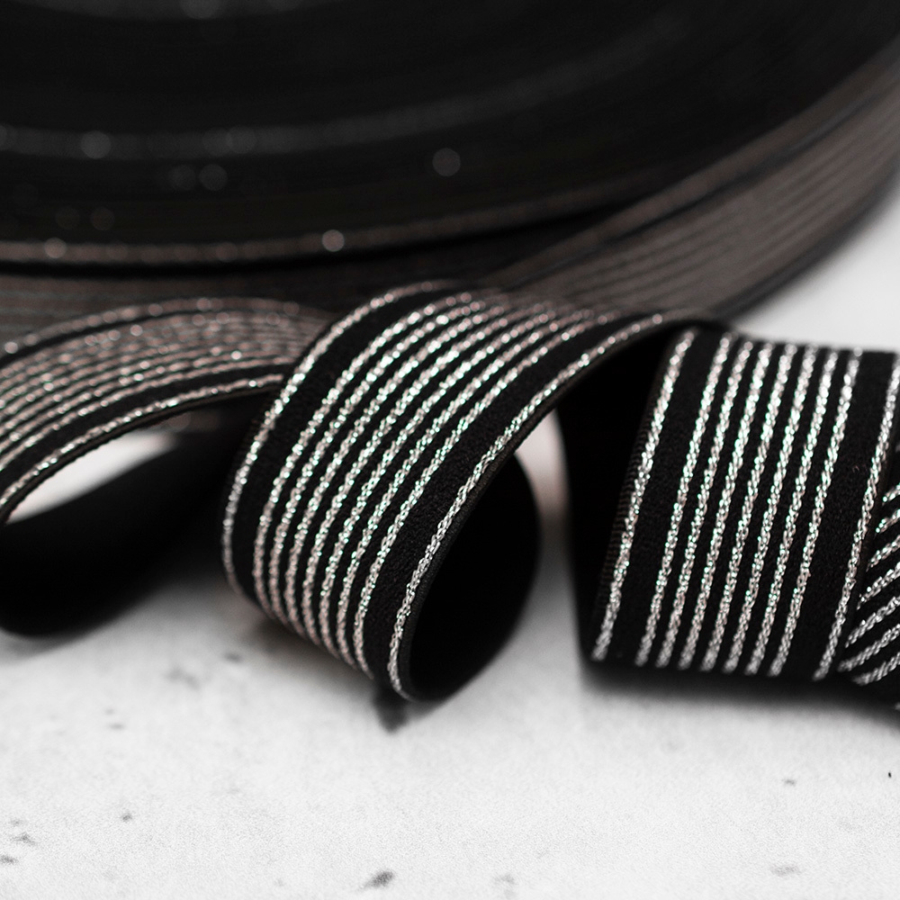 Ozdobna gumowa taśma w kolorze czarnym, ozdobiona dodatkowo metalicznym wzorem w postaci drobnych pasków.