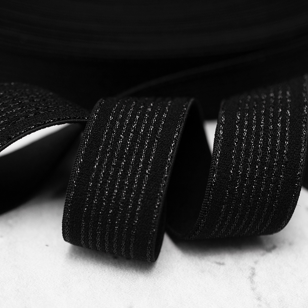 Ozdobna gumowa taśma w kolorze czarnym, ozdobiona dodatkowo metalicznym wzorem w postaci drobnych pasków.