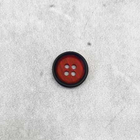 Plastikowy guzik z czterema dziurkami, w kolorze czerwonego drewna, z czarna obwódką.