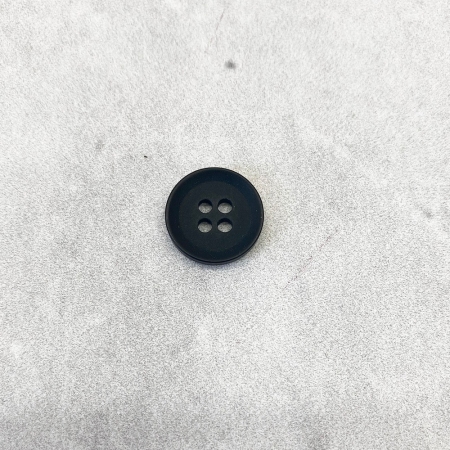 Plastikowy guzik z czterema dziurkami, w kolorze czarnym.