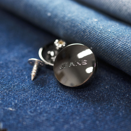 Guzik metalowy w kształcie koła o średnicy 2 cm.