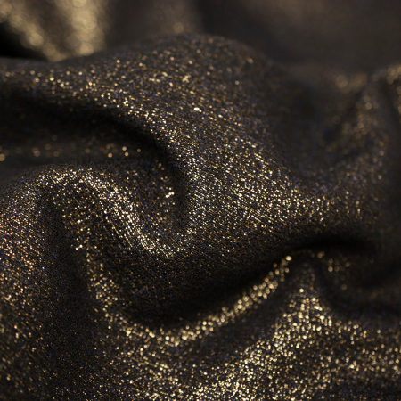 Efektowna metaliczna tkanina w głębokim odcieniu czerni przyciąga wzrok wyrazistą złotą nitką, która nadaje mu luksusowy charakter.