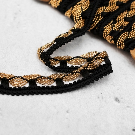 Dekoracyjna taśma w kolorze czarnym, ozdobiona złotym łańcuszkiem, który tworzy kształt fali.