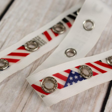 Dekoracyjna taśma rypsowa ozdobiona srebrnymi oczkami i taśmą z motywem flagi USA.