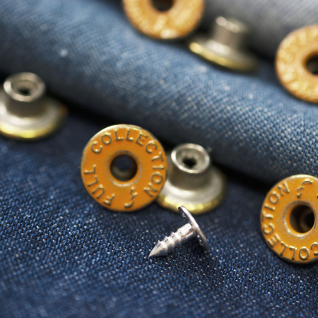 Guzik metalowy w kształcie koła o średnicy 1,4 cm.