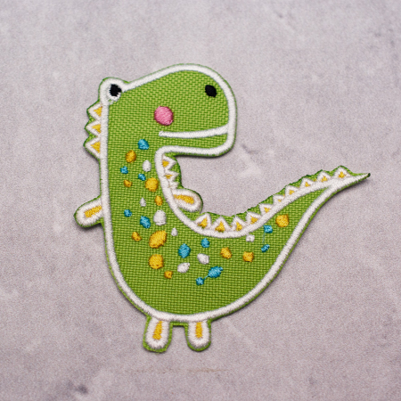 Aplikacja termoprzylepna SWEET DINO w kolorze zielonym o wymiarach: 8 cm x 8 cm.