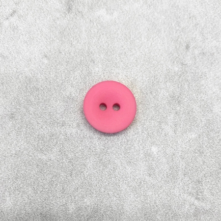 Plastikowy guzik z dwiema dziurkami, w kolorze różowym.